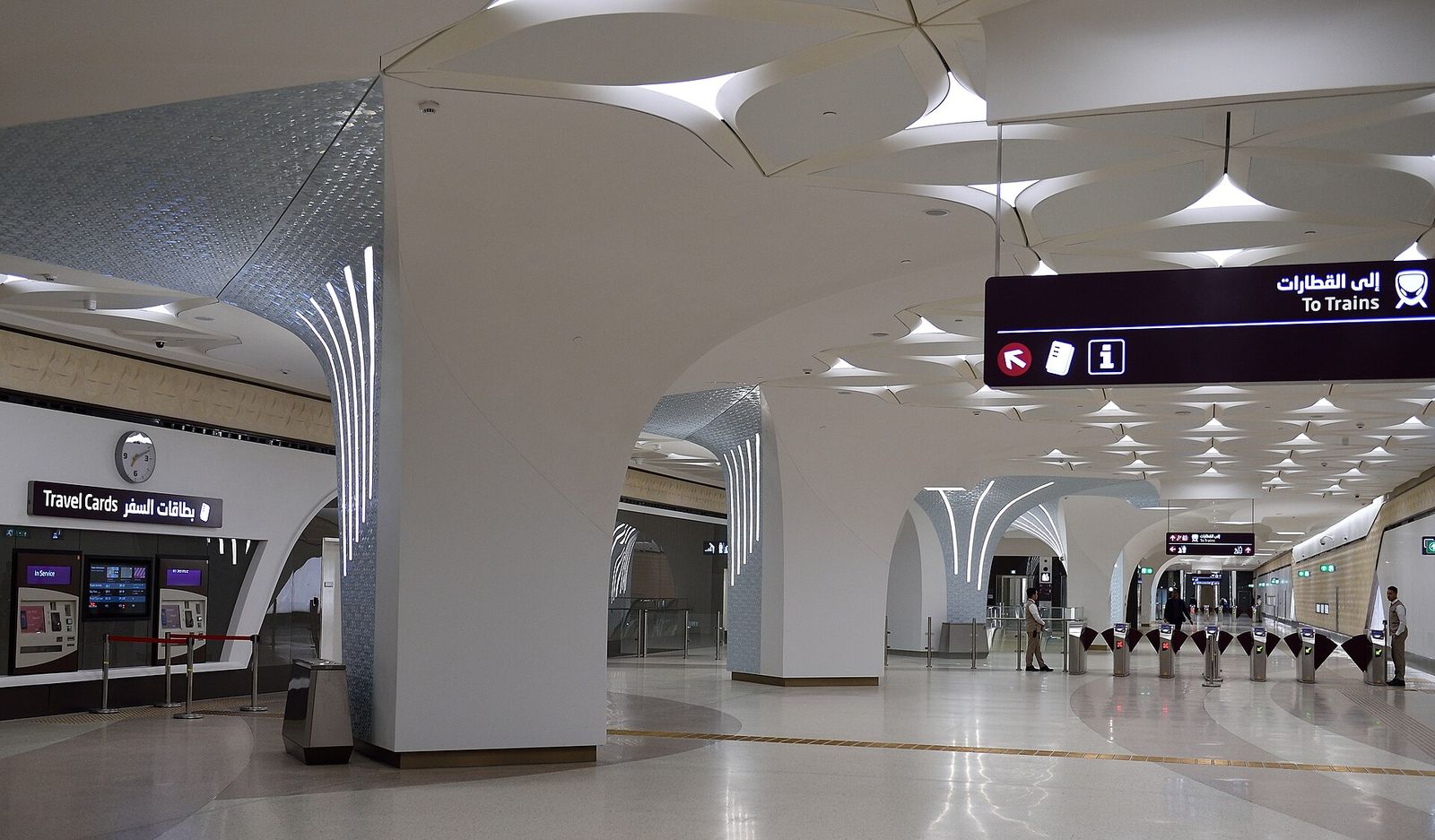 Ticket gates and white vaulted ceiling inside a Doha Metro station concourse