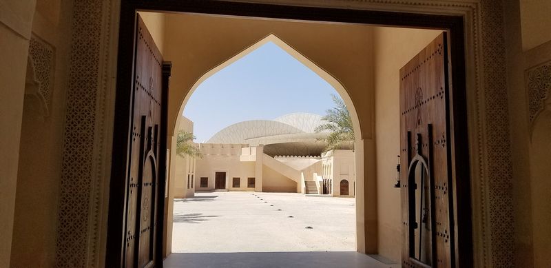 The disc-shaped roof of the National Museum of Qatar seen through an arched wooden gateway