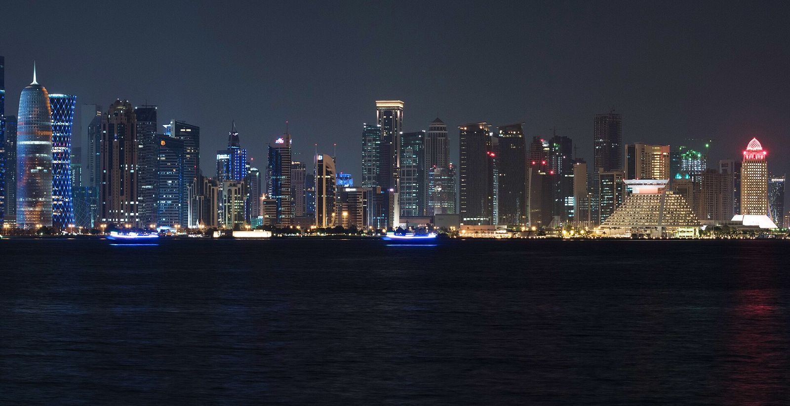 Doha's West Bay skyline lit up at night and reflected in the dark water of Doha Bay